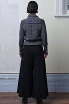 Back full body view of model wearing a chunky knit wool ruched cardigan in a grey with white flecked colourway.