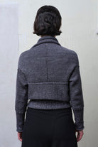 Back view of model wearing a chunky knit wool ruched cardigan upside down, in a grey with white flecked colourway.