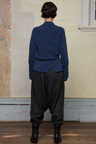 Backview of model wearing wool boucle knitted jumper in blue with orange external seams.
