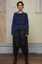 Front view of model wearing wool boucle knitted jumper in blue with orange external seams.