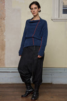 Front view of model wearing wool boucle knitted jumper in blue with orange external seams.