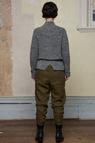 Back view of model wearing wool boucle knitted jumper in grey melange with decorative external seam details.
