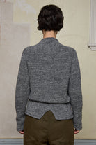 Back view of model wearing wool boucle knitted jumper in grey melange with decorative external seam details.