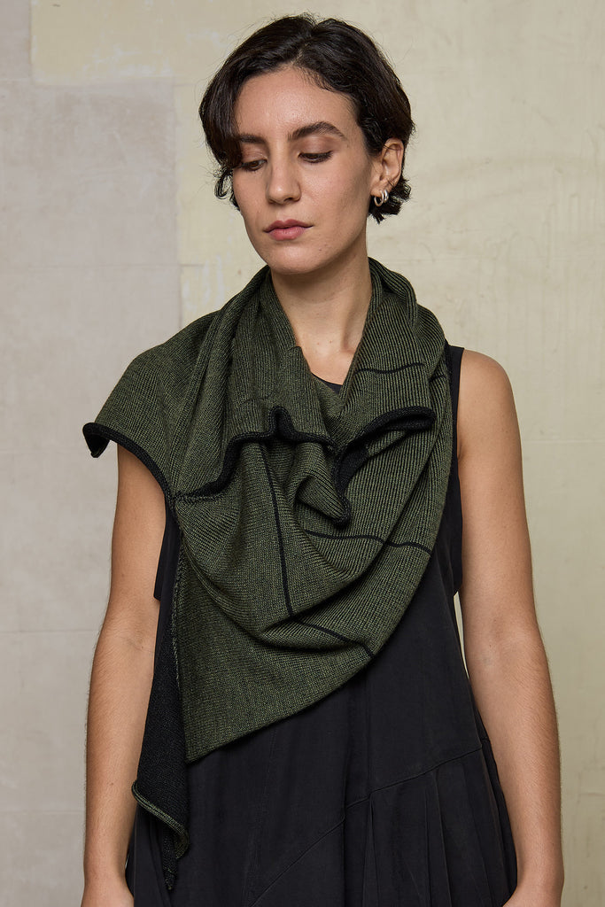 Model wears knitted asymmetric self-curling vest as a scarf, in army green on black colourway. Designed and knitted in Melbourne by Wendy Voon knits.