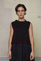 Model wears knitted asymmetric self-curling vest inside out, in burgundy on black colourway. Designed and knitted in Melbourne by Wendy Voon knits