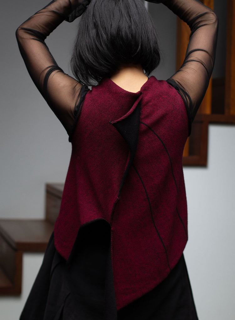 Back view of model wearing an asymmetric self-curling vest back to front.  Vest is knitted in superfine merino wool,in a maroon backed with black colourway, designed and knitted in Melbourne by Wendy Voon knits.