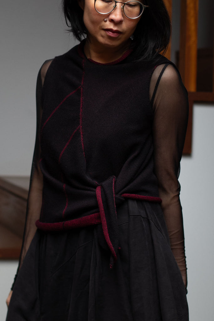 Model is wearing an asymmetric self-curling vest inside out and tied at the waist.  Vest is knitted in superfine merino wool,in a maroon backed with black colourway, designed and knitted in Melbourne by Wendy Voon knits.