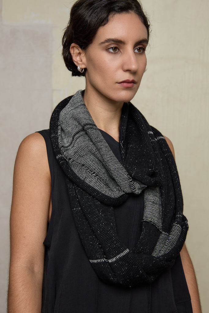 Model wears knitted black and white infinity scarf, made from alpaca, merino wool and cotton