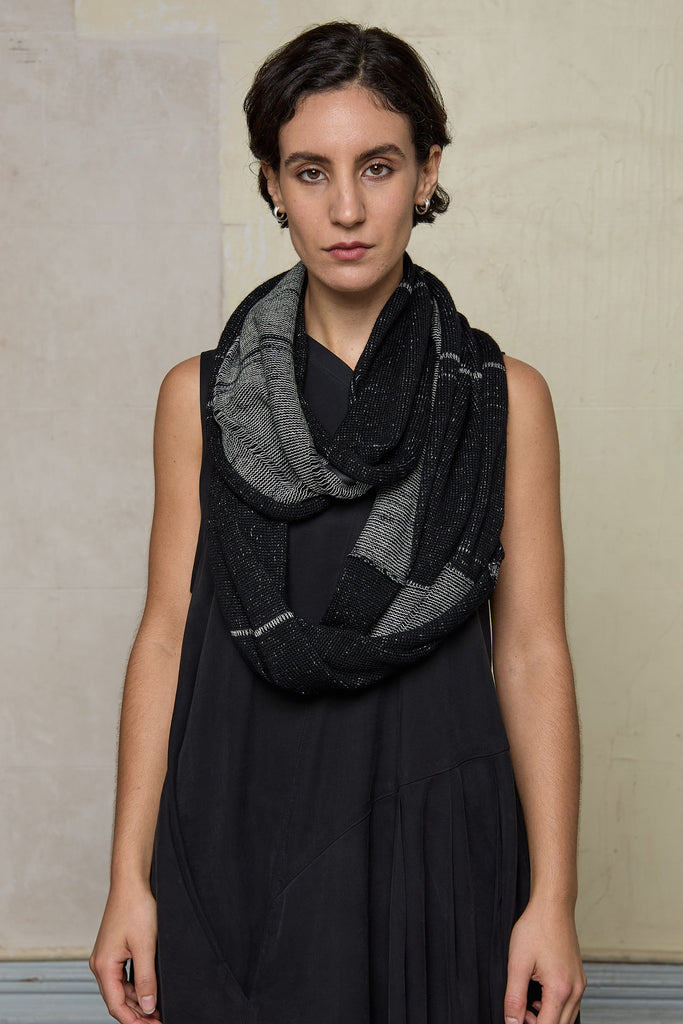 Model wears knitted black and white infinity scarf, made from alpaca, merino wool and cotton