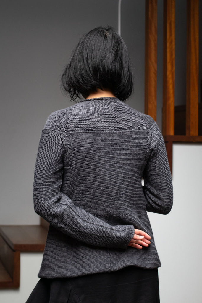 Back view of model wearing a knitted steel grey peplum riding coat, made from a chunky superfine merino yarn. This piece is designed and made in Melbourne by Wendy Voon knits. 