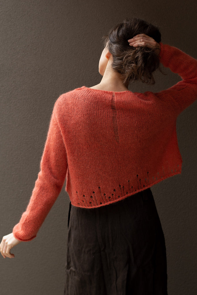 Backl view of super soft knitted jumper in a carrot colour way, featuring laddered laceholes, made from baby alpaca, mohair and silk. Designed and made in Melbourne by Wendy Voon knits