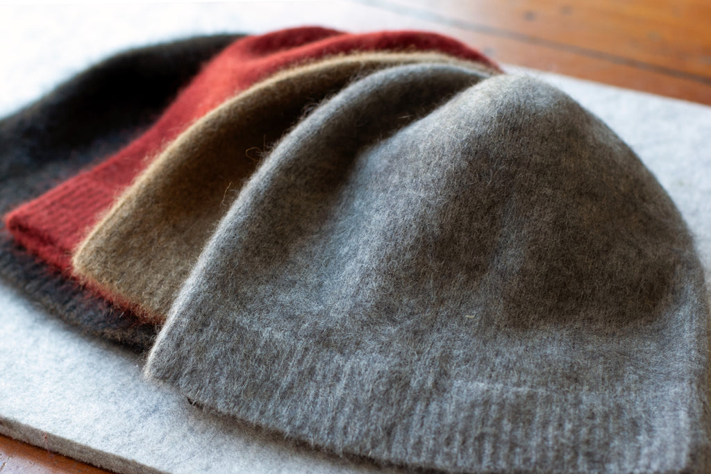 Group of coloured knitted beanie made from merino wool, possum and silk. Colours are dark tawny, burnt red, camel and light grey