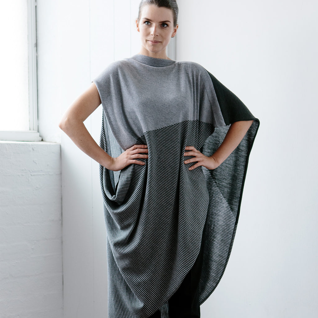 Front view of Striped Wrap design by Wendy Voon knits in grey and deep forest merino wool, worn as asymmetric poncho