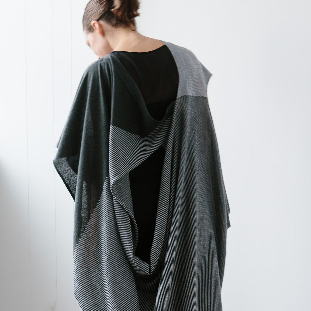 Back view of Striped Wrap design by Wendy Voon knits in grey and deep forest merino wool, worn as asymmetric poncho