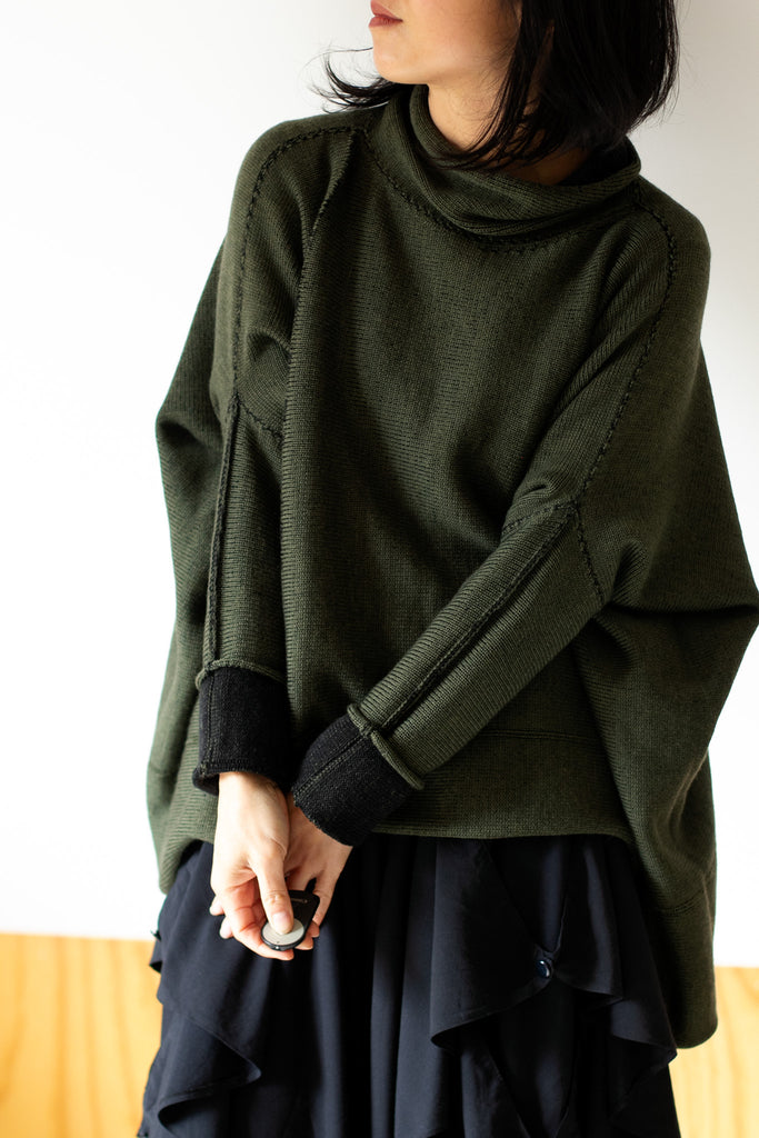 Front view of box shaped jumper designed by Wendy Voon, in army green with black backed fabric, made from superfine merino wool.